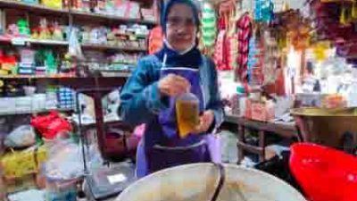 Yuli salah satu pelayan di Toko Sembako Handoko Pasar Pagi Kota Cirebon, Jawa Barat, menunjukan minyak goreng curah yang baru saja dia bungkus, Senin (27/6/2022).(KOMPAS.com/MUHAMAD SYAHRI ROMDHON)